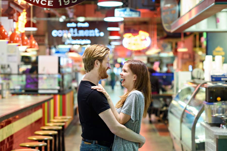 A man hugs his fiance during engagement session in Reading Terminal Market in Philadelphia.